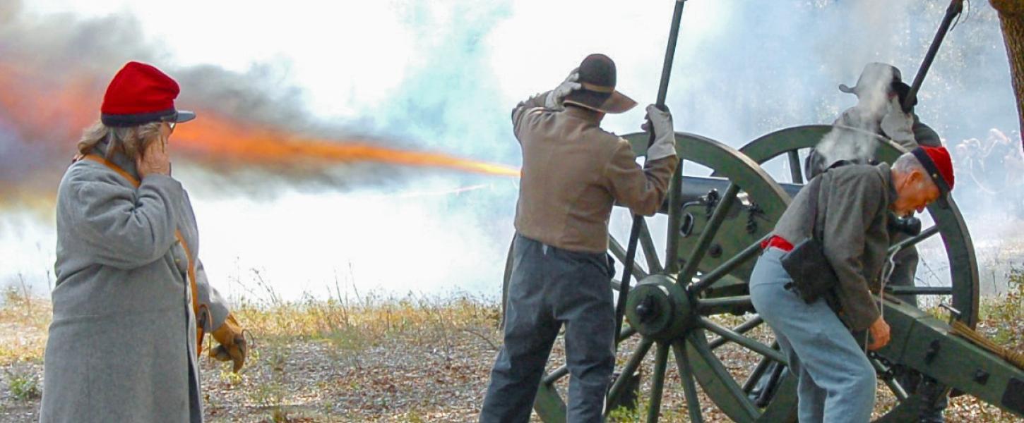 A team of reenactors firing a cannon. 