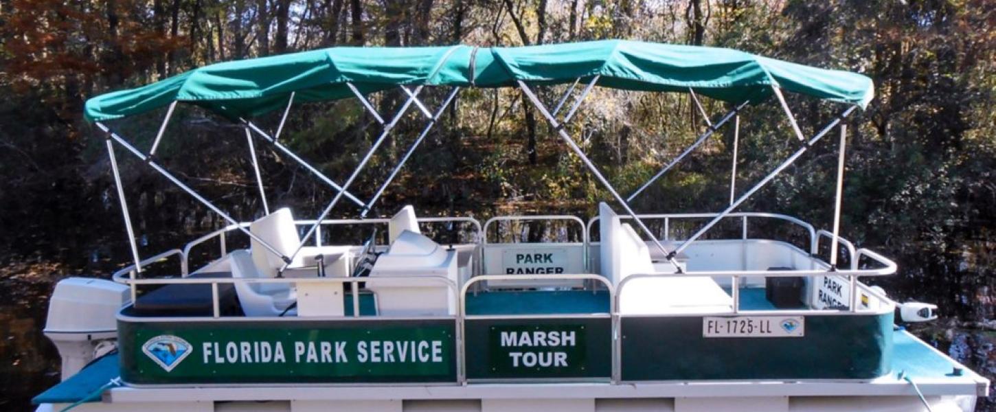An empty green and white pontoon boat sits in the water