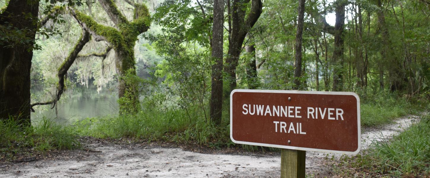 The Suwannee River Trail sign in front of the trail