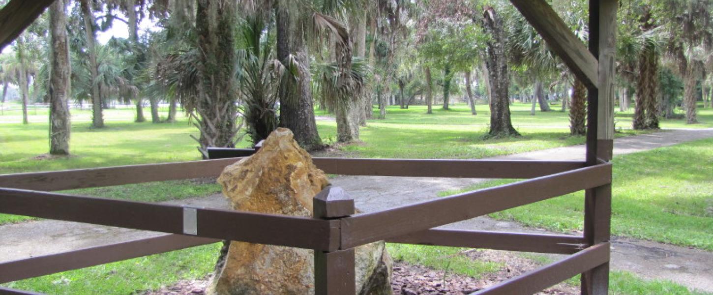 A large limestone rock sits behind a fence enclosure.