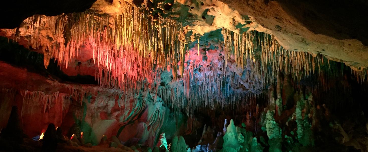 View of inside the caverns with colorful lights accenting the natural stalagtites