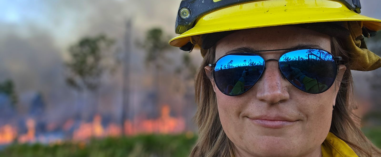 A woman wearing protective fire safety equipment and reflective aviator sunglasses.
