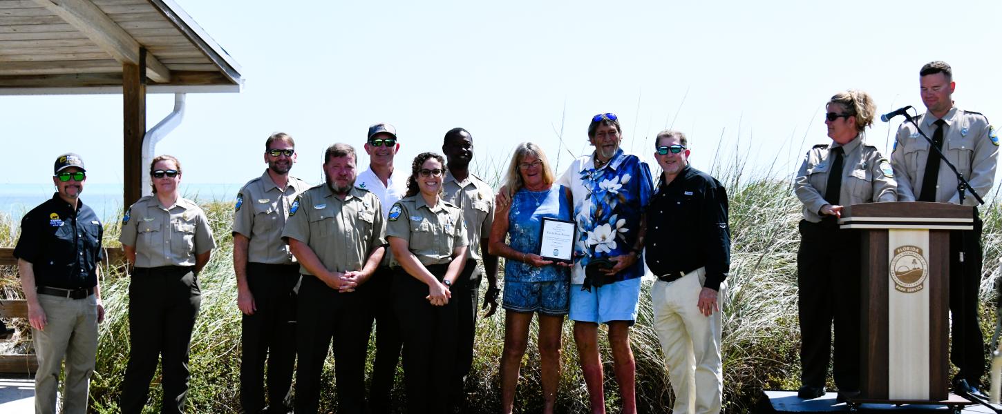 volunteers hold their plaque award while surrounded by park staff