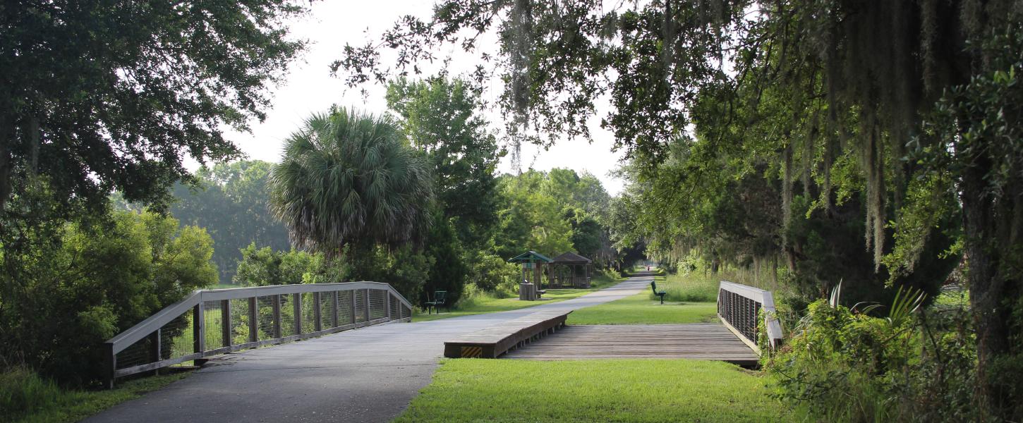 A bridge crosses a small ditch along a green pathway.