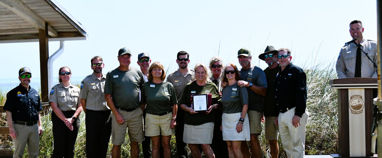volunteers stand with plaque award surrounded by park staff