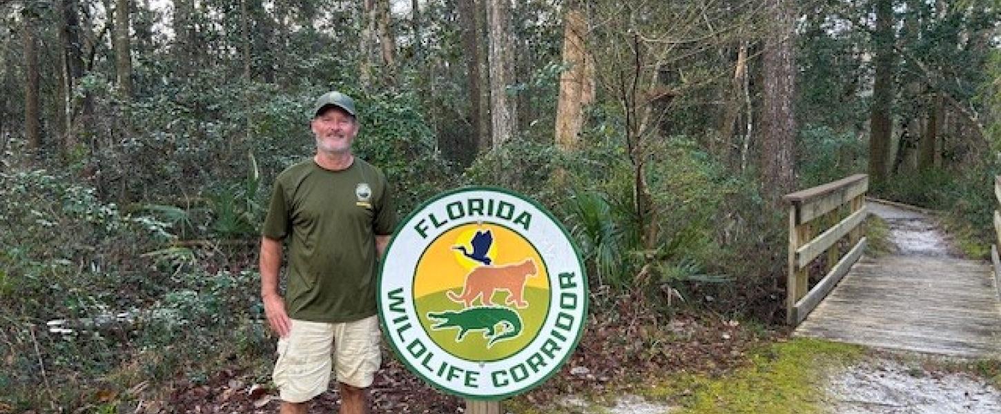 Jim Quyle in front of the Florida Wildlife Corridoor photo.
