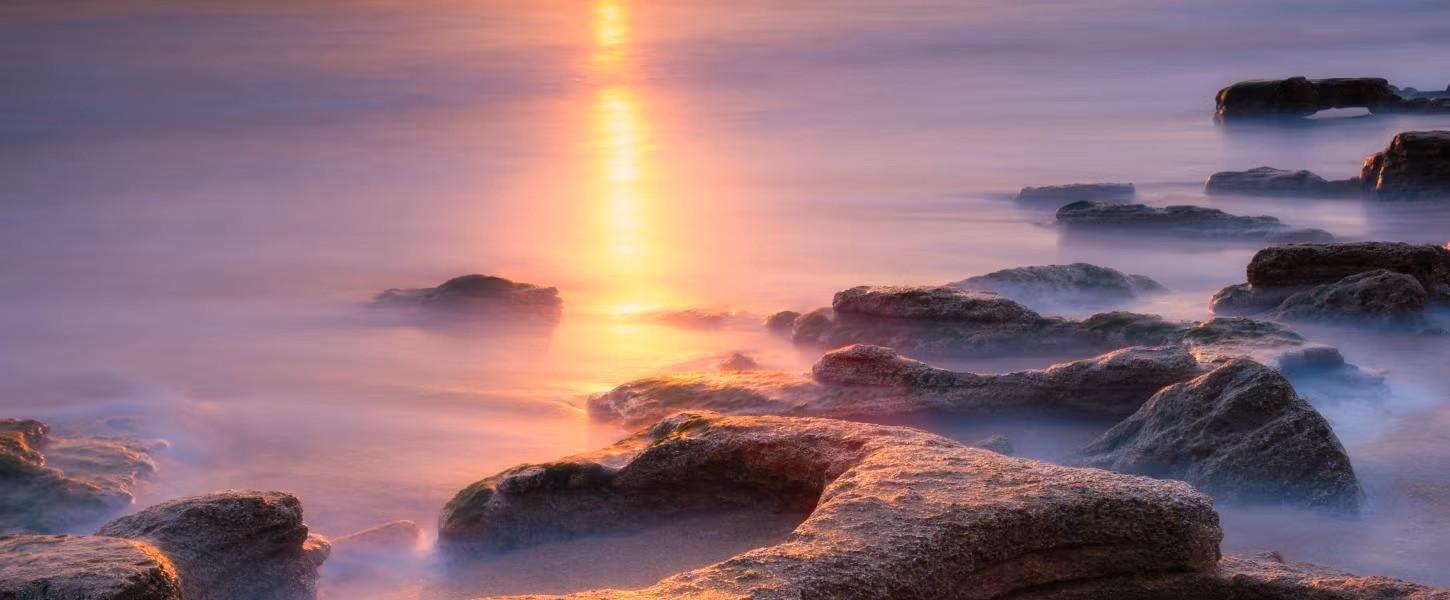 Waves gently flowing over coquina rocks at sunrise. 