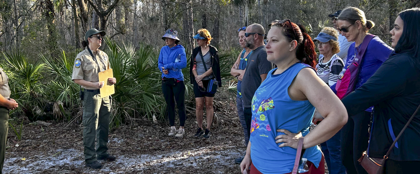 A group of hikers on the trail paused to listen to two rangers speaking. 