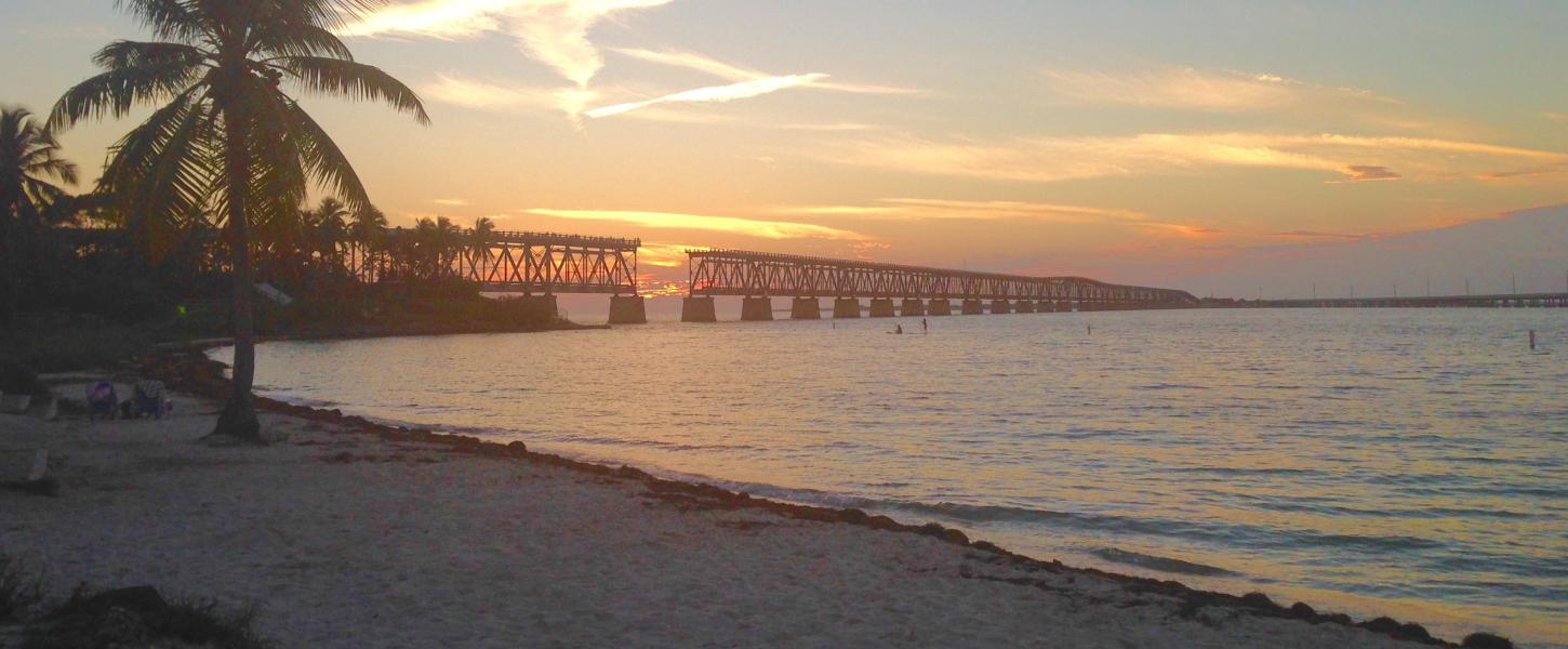 A view of the beach at sunset with the bridge in the background.