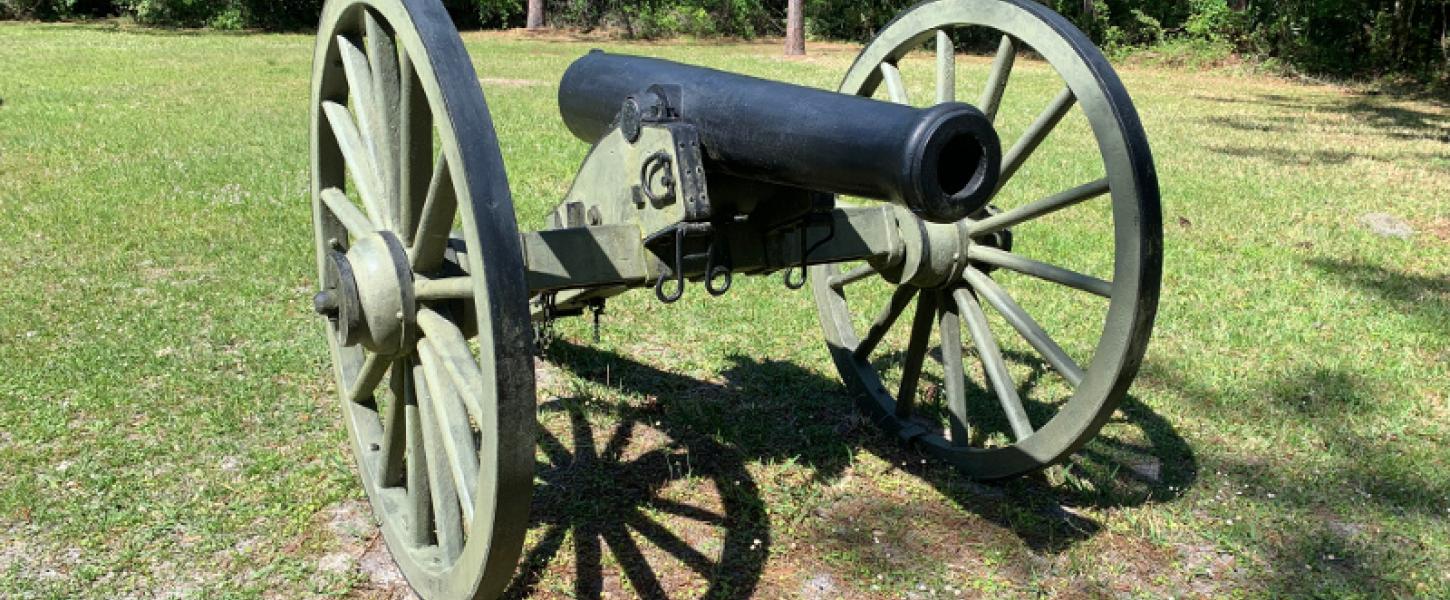 a large cannon on wheels stands on the grass