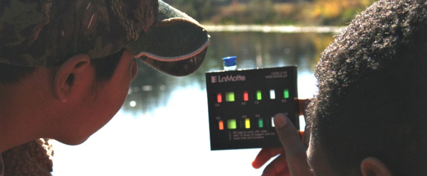 Two boys looking at a water testing device.