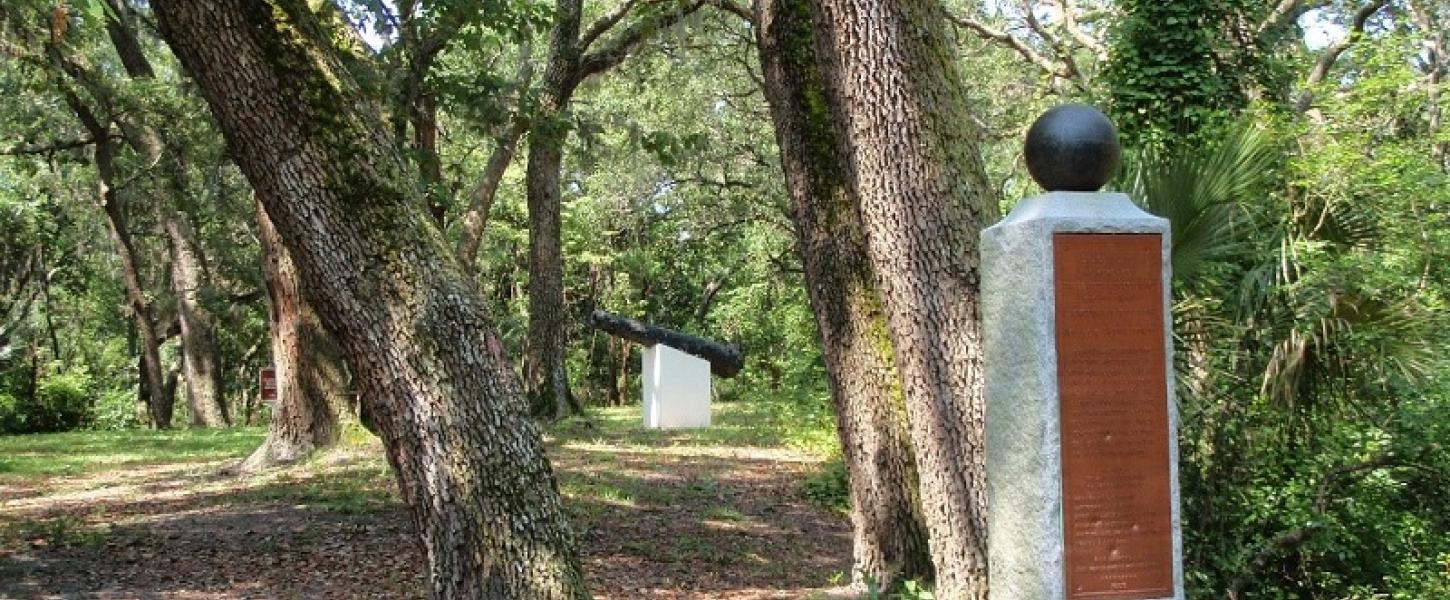 a monument, trees, and cannon at yellow bluff fort historic state park