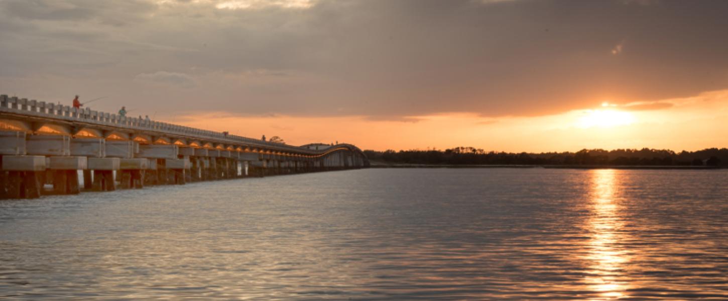 a view of a long concrete bridge at sunset