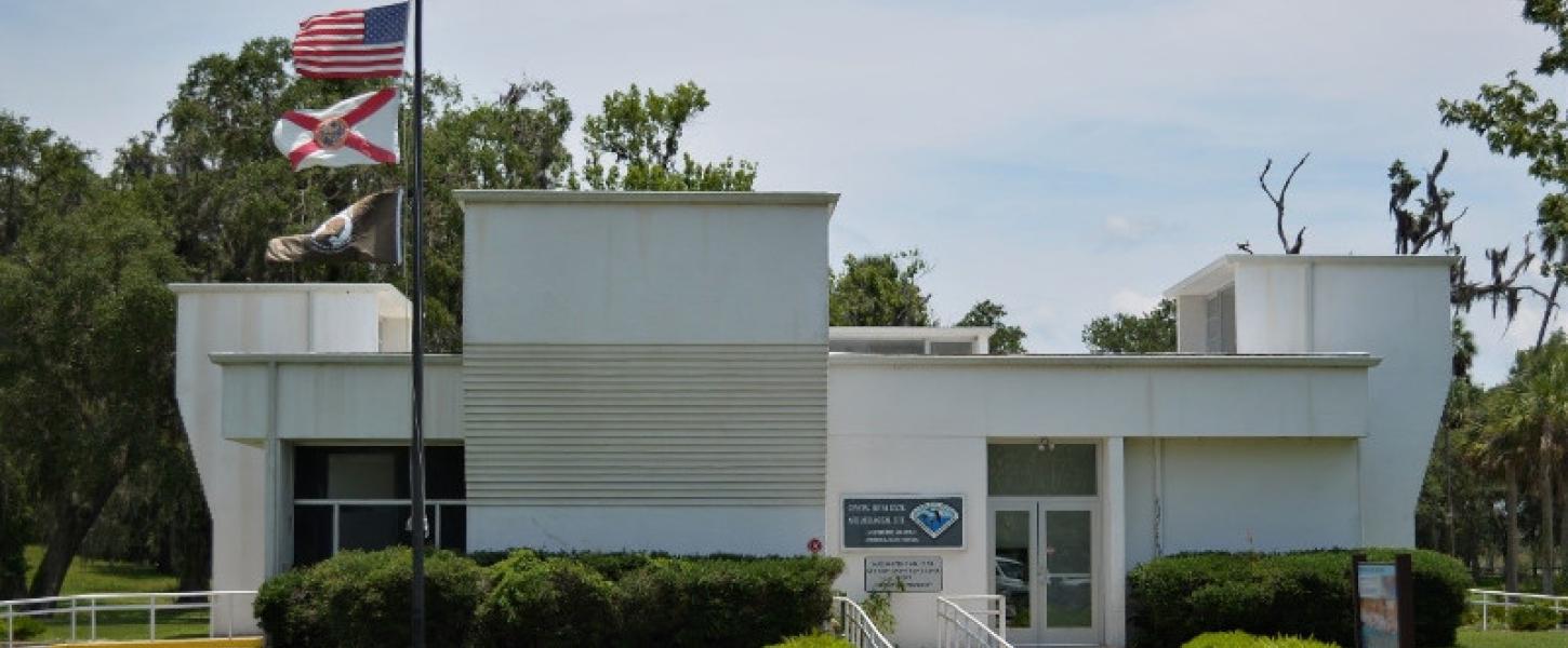 a large white building with irregular shapes, flying the state and American flags.