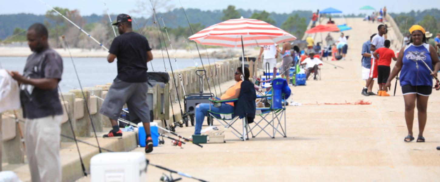 large crowds of people fish off of a long concrete bridge