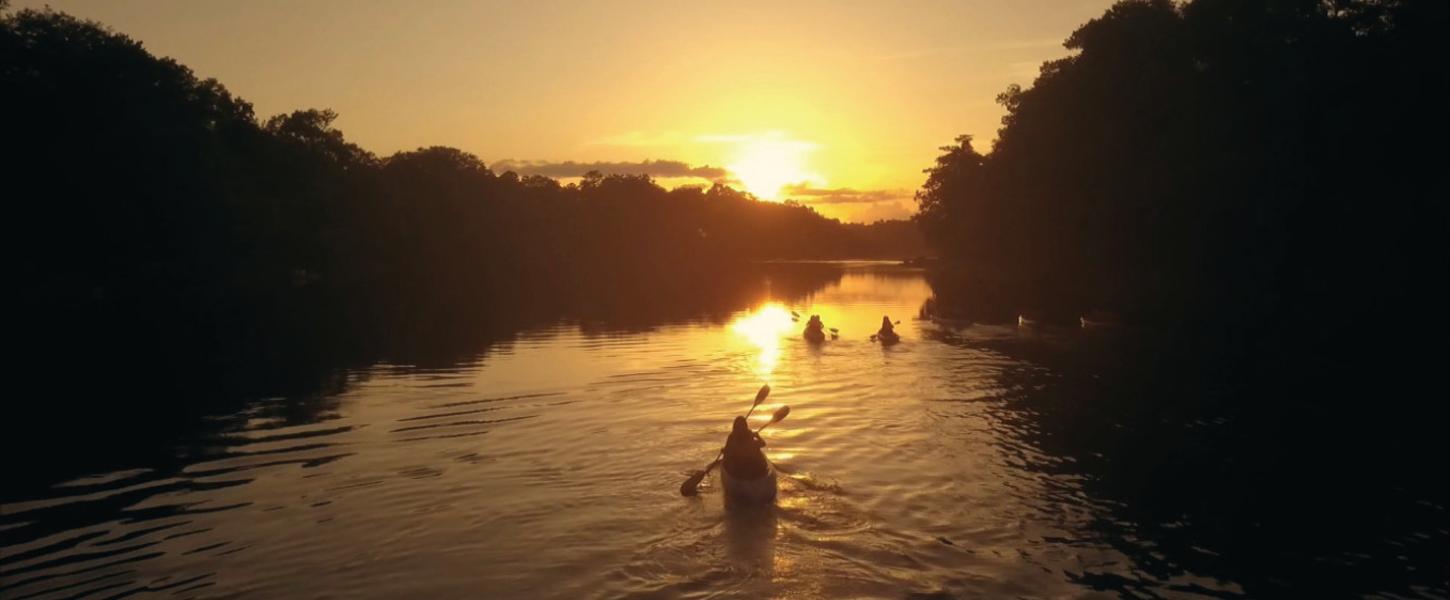 Image of three kayaks/canoes padding the Suwannee River at sunset