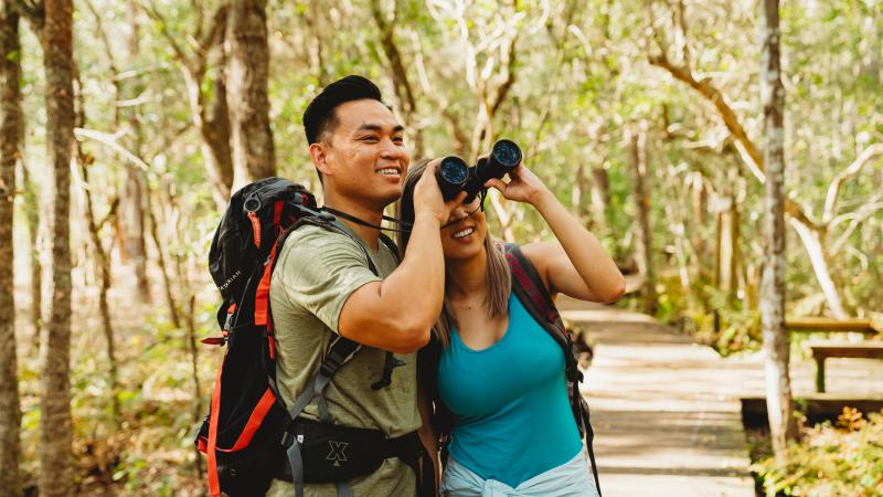 A man and woman look through binoculars to see a bird at Lake Louisa State Park.