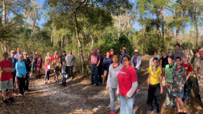 a large group of people waits to go on a guided hike on a trail