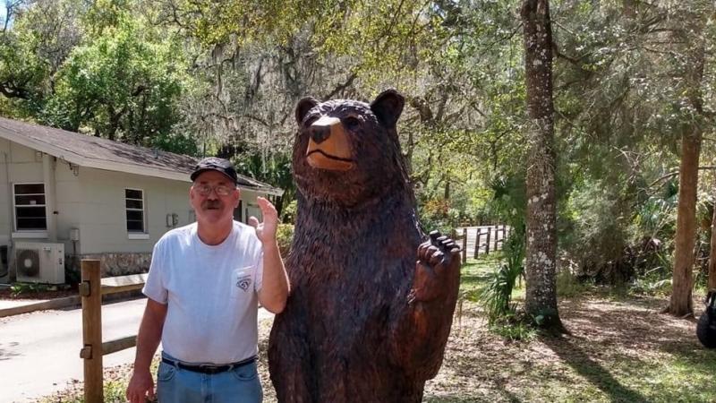 Dennis Bryant poses with a bear statue at the park.