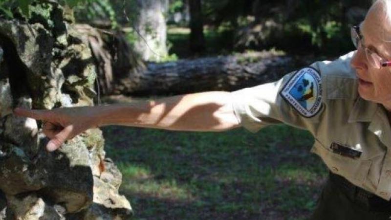 Kristin, pointing to a rock, wearing her ranger uniform.