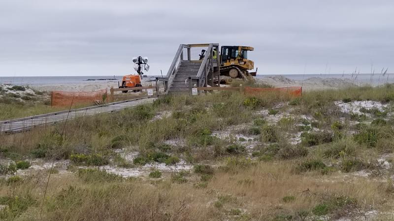 A bulldozer pushes sand on the beach.