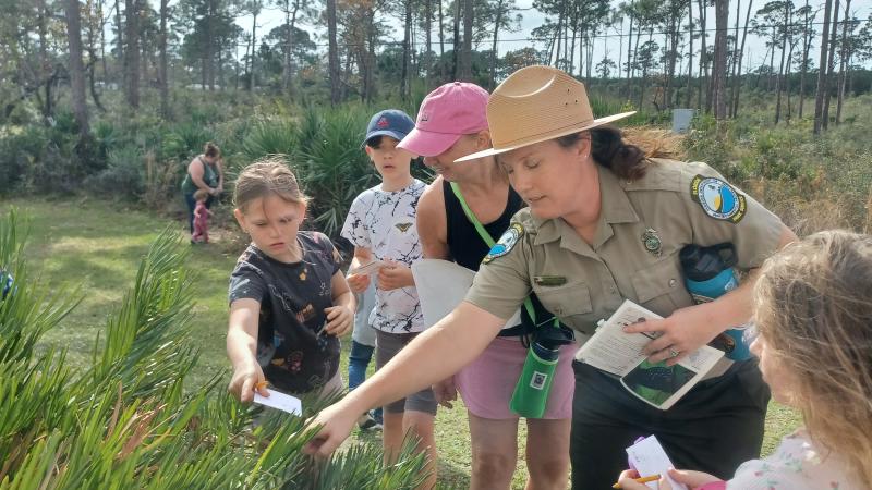 Image of Park Ranger with children observing butterflies in a plant.