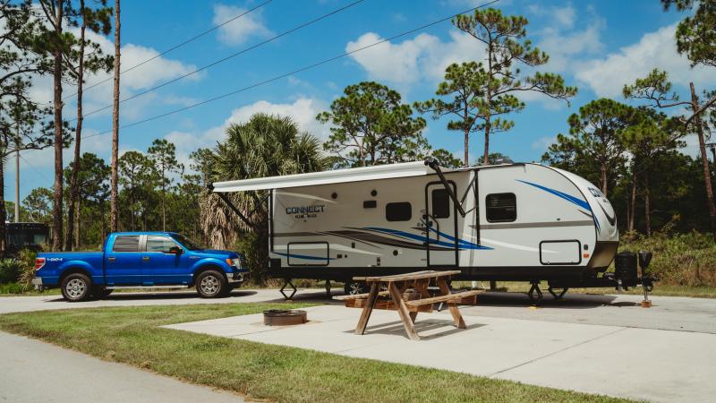 A camper and truck are set up on a concrete pad.