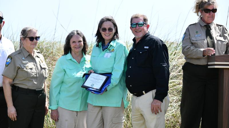 volunteers smile while holding award plaque surrounded by park staff