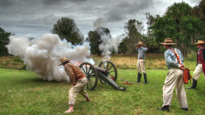 4 Reenactment actors standing around a cannonball firing 