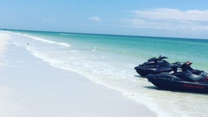 A view of two speedboats on the edge of the water along the beach.