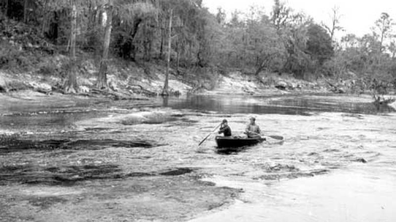 A historical photo of two paddlers in a canoe in Big Shoals. 