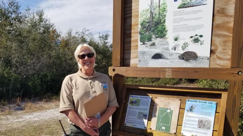 Dora poses beside an interpretive panel at the park.