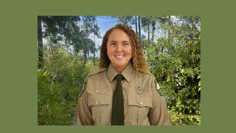 Park Ranger Lauren Sheppard in her uniform standing in the woods.