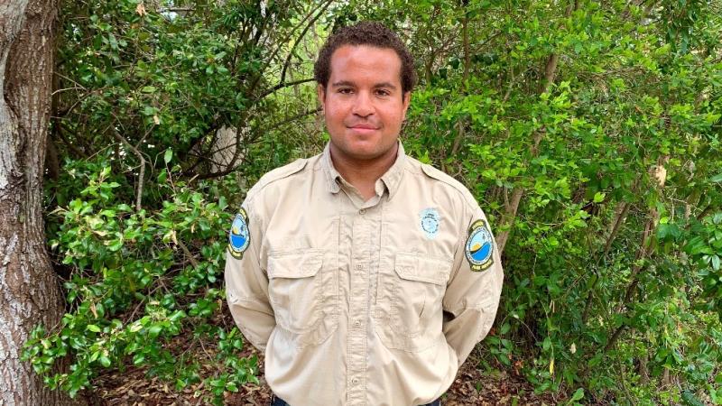 Ranger Chris Herald stands in front of greenery.