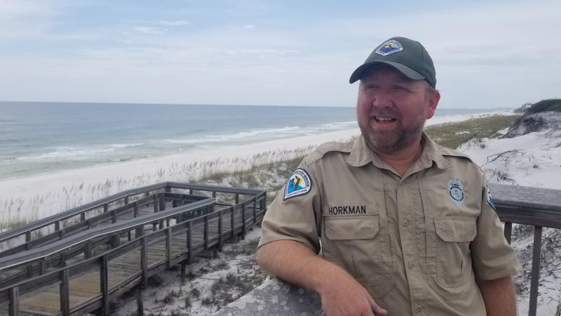 Chris, a Florida Park Ranger on a boardwalk, overlooking the ocean.