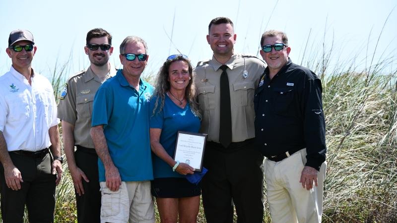 volunteers smile while holding their plaque award surrounded by park staff