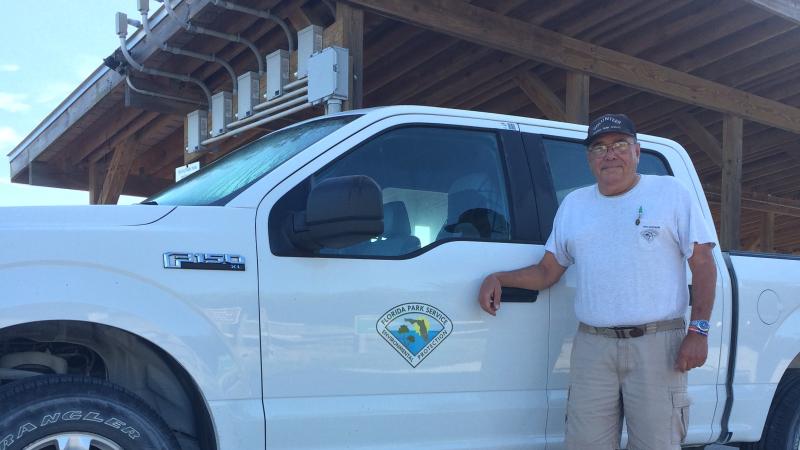 Dennis, standing by a truck, smiling at the camera.