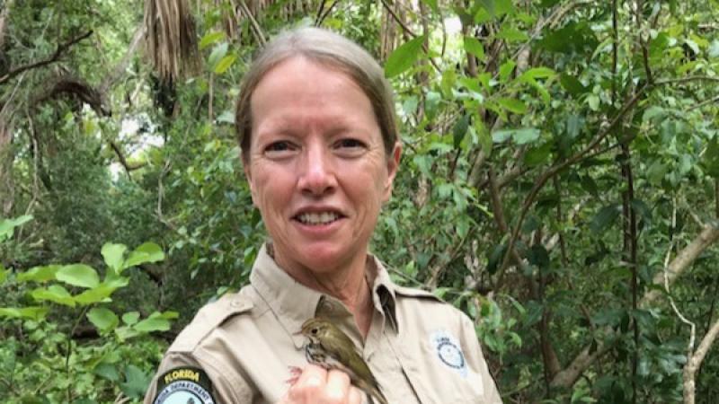 Biologist Elizabeth Golden holds a songbird.