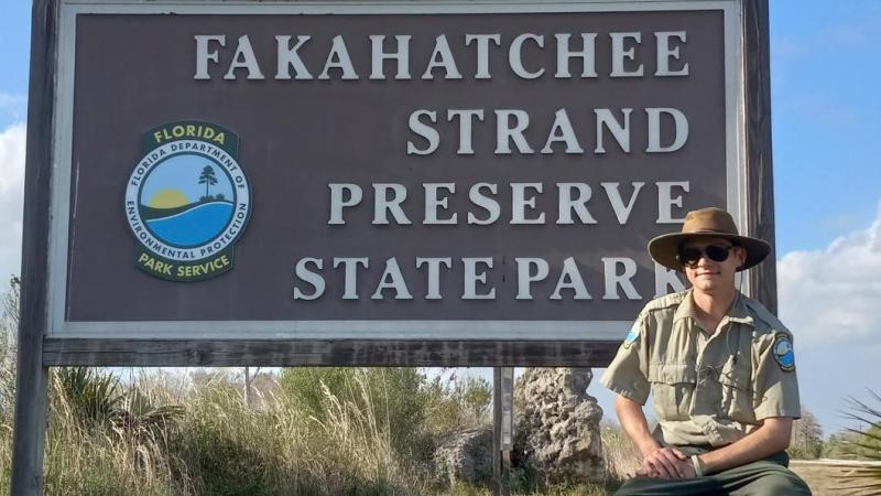 William Greene posing for a photo next to the Fakahatchee Strand Preserve State Park entrance sign.