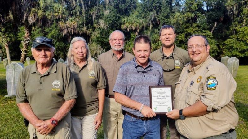 Members of the Friends group and the park manager showing off an award.