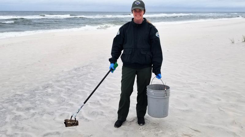 Jessica Ryan picking up trash along the beach.