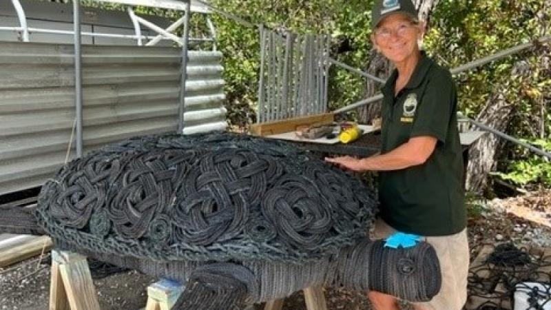 Jill Long poses with Myrtle, a sea turtle sculpted from debris.