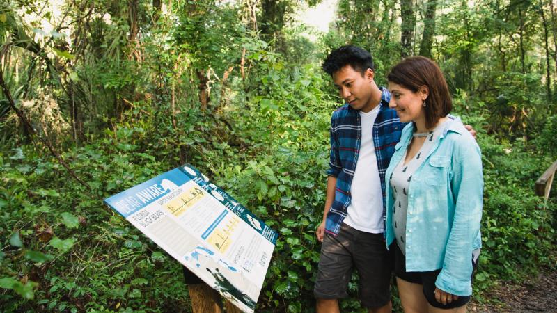 Couple reading kiosk on trail at Rainbow Springs State Park.