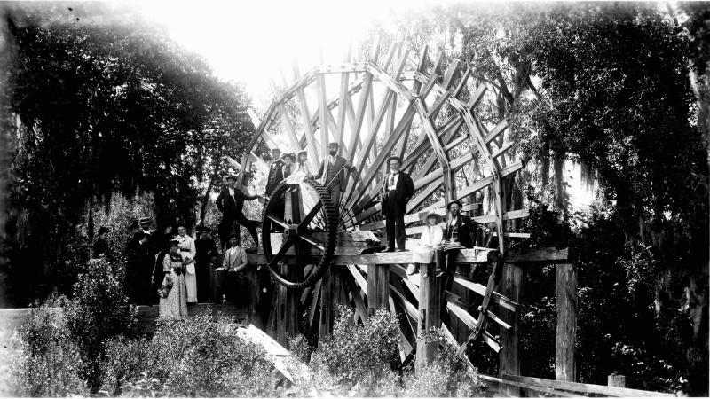 Black and White photo of people standing on the De Leon Springs sugar mill wheel