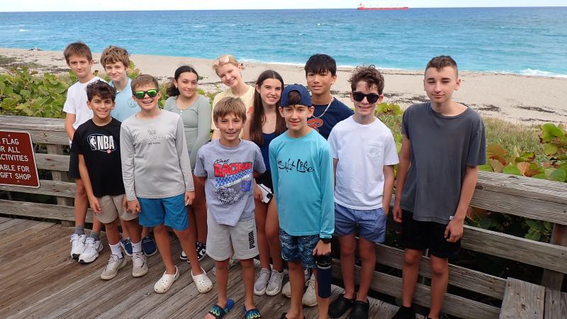 young volunteers stand together on a boardwalk overlooking the ocean