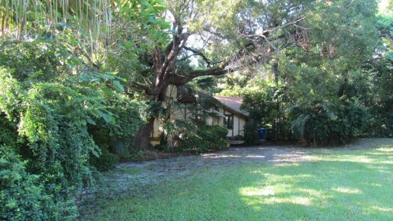 The Marjory Stoneman Douglas House nestled under tall trees with a green lawn. Credit: James Gabbert, National Park Service