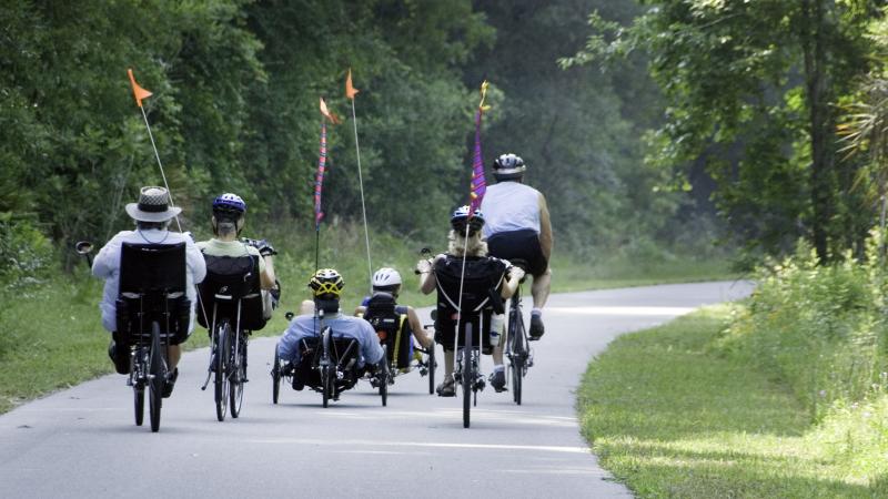 A group of bicycle riders on a paved trail. 