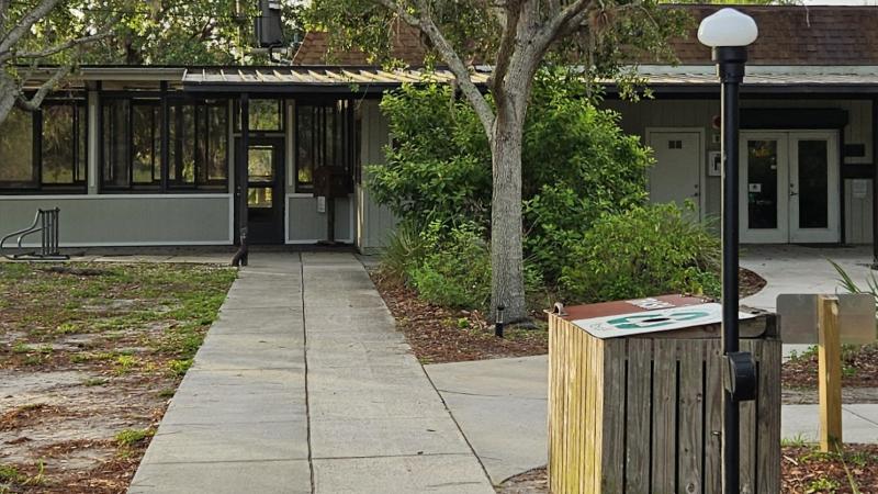 A pathway leading to a low gray and brown building. 