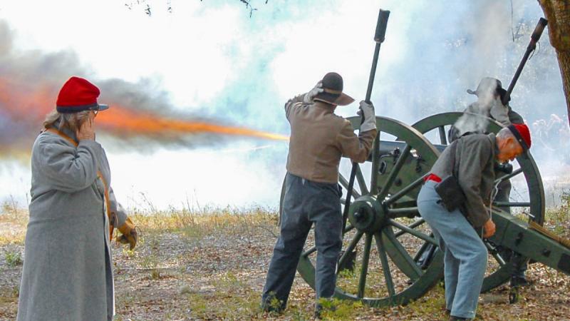 A team of reenactors firing a cannon. 