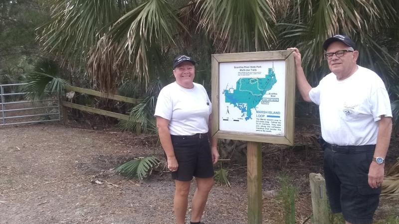 Volunteer Nick and Darlene Divirgilio pose next to trail sign at Econfina River State Park. 